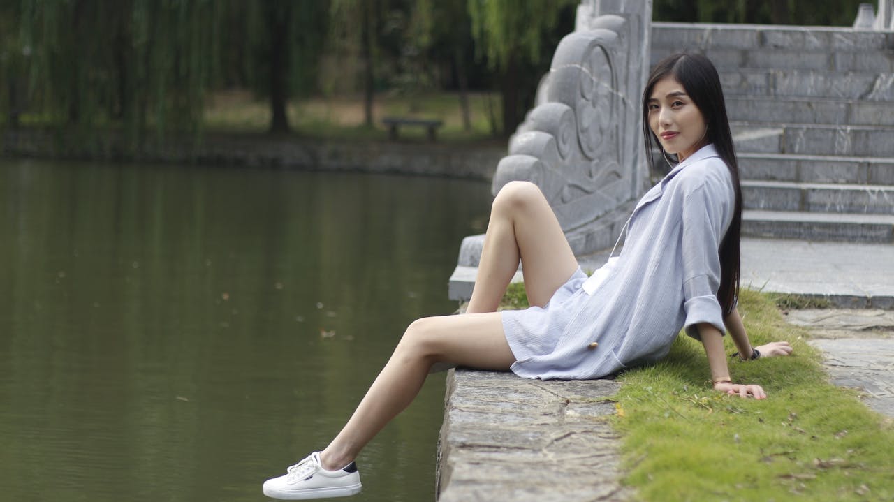 Asian woman enjoying leisure time by a serene lake in summer.